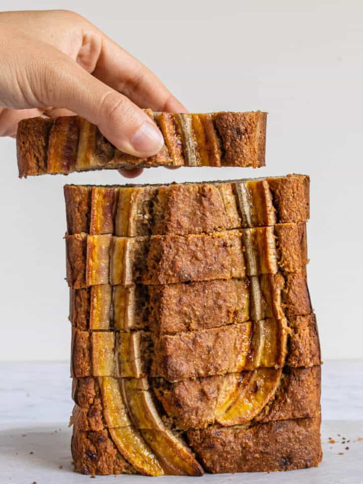 One piece of Healthy Banana Bread being picked up from a stack