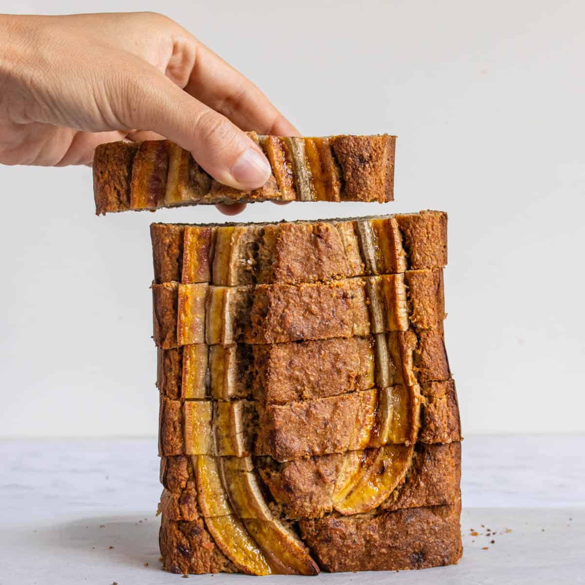 One piece of Healthy Banana Bread being picked up from a stack
