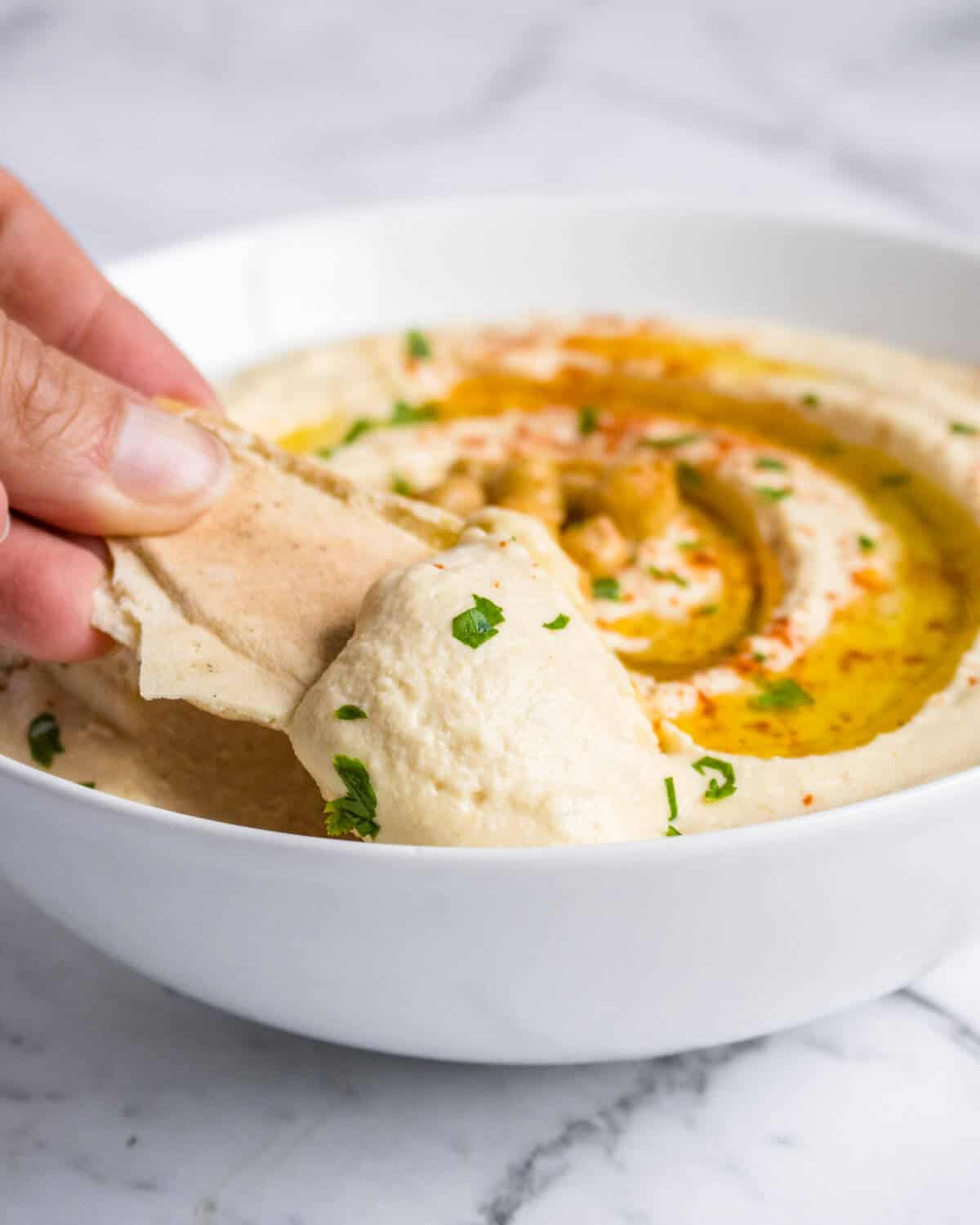 Hummus being dipped with a pita chip