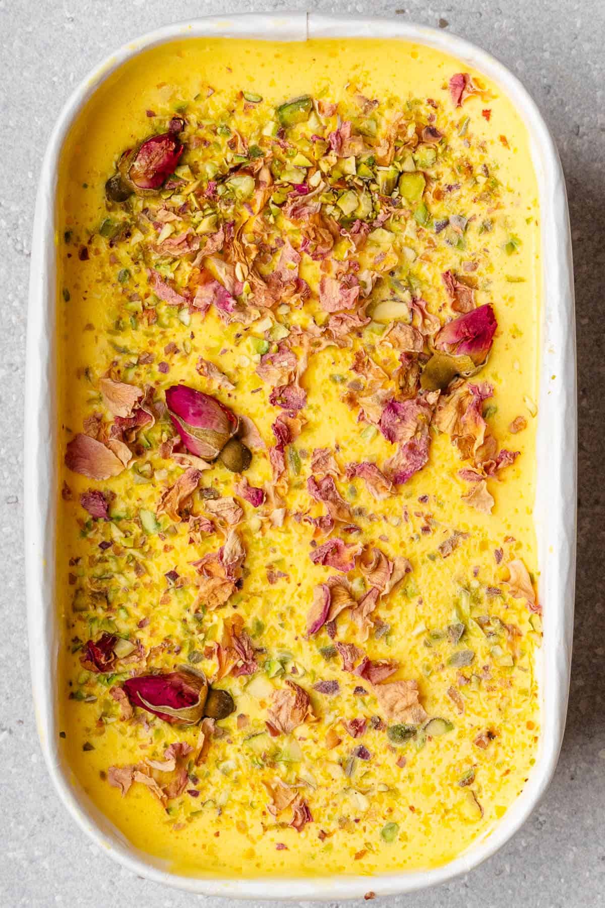 Tub of frozen Persian Ice cream topped with pistachios and rose petals