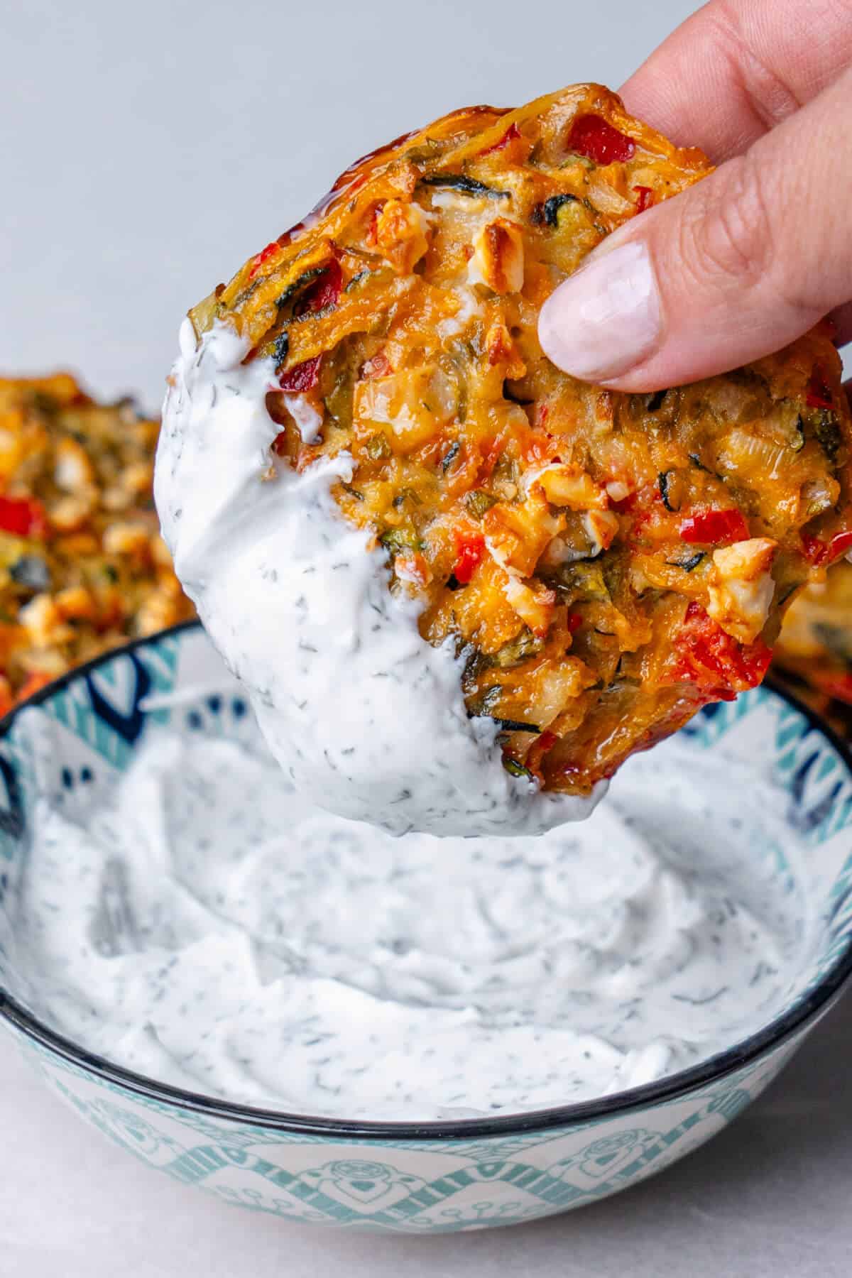 A vegetable fritter dipped into a yoghurt sauce