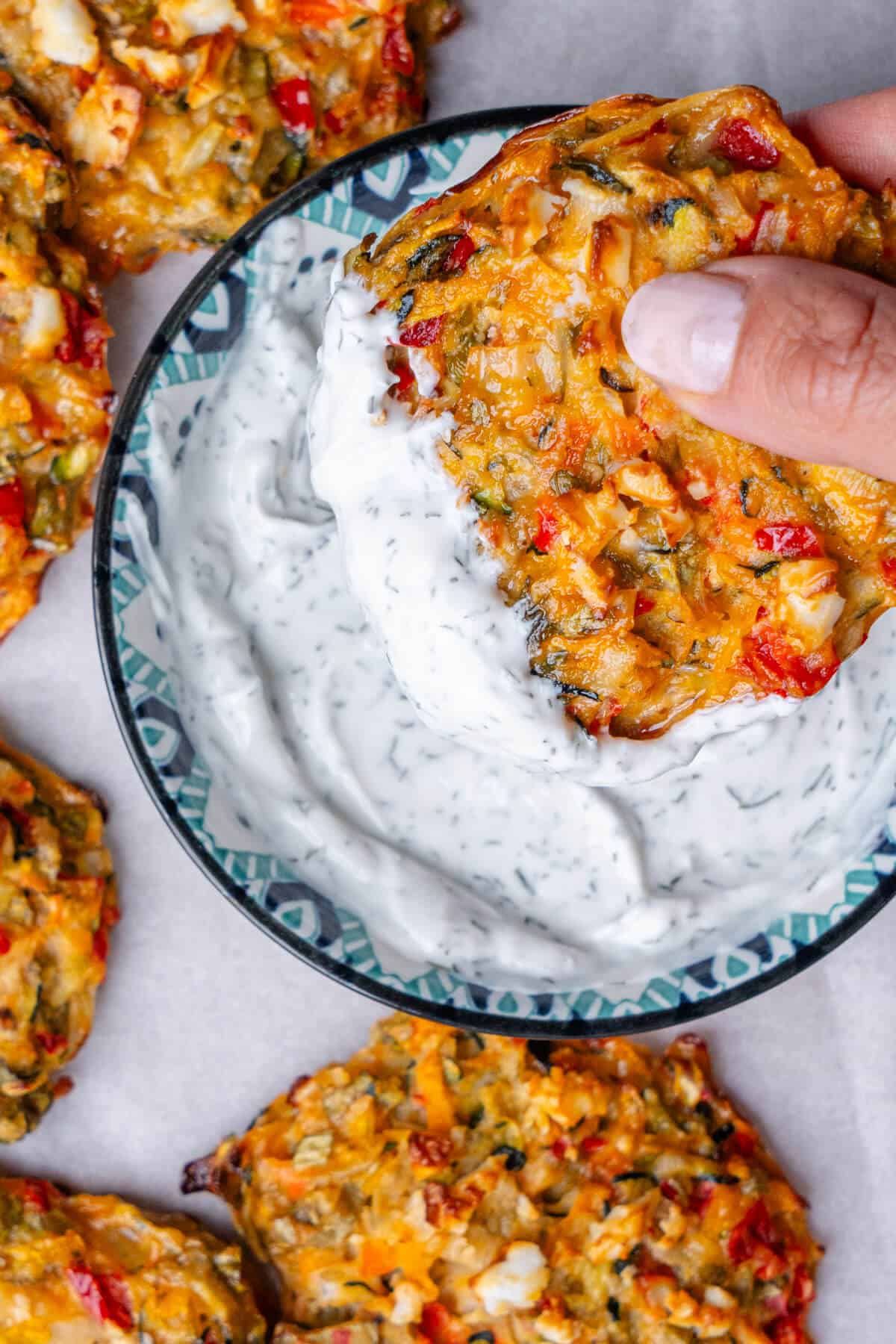Veggie fritter being dipped into a yoghurt sauce