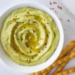 Avocado hummus topped with olive oil and chilli flakes served with crackers