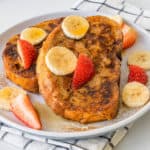 Healthy french toast served with slices of banana, strawberries, maple syrup and a light dusting of cinnamon