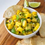 Mango avocado salsa served in a bowl with lime and corn chips