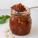 Spoon full of recipe sun dried tomato pesto over a jar