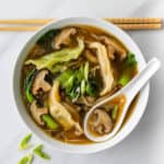 Shiitake broth and dumpling soup in a bowl with serving spoon and chopsticks