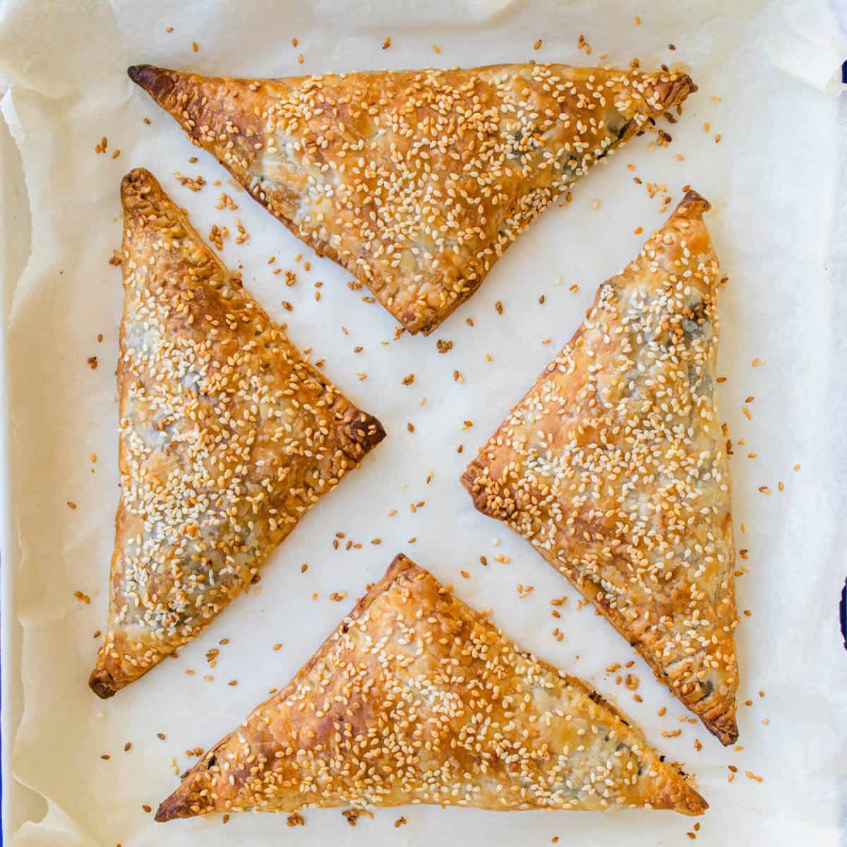 Baked spinach and feta triangles on an oven tray