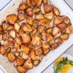 Crispy roasted potatoes recipe in an oven dish with garlic oil on the side