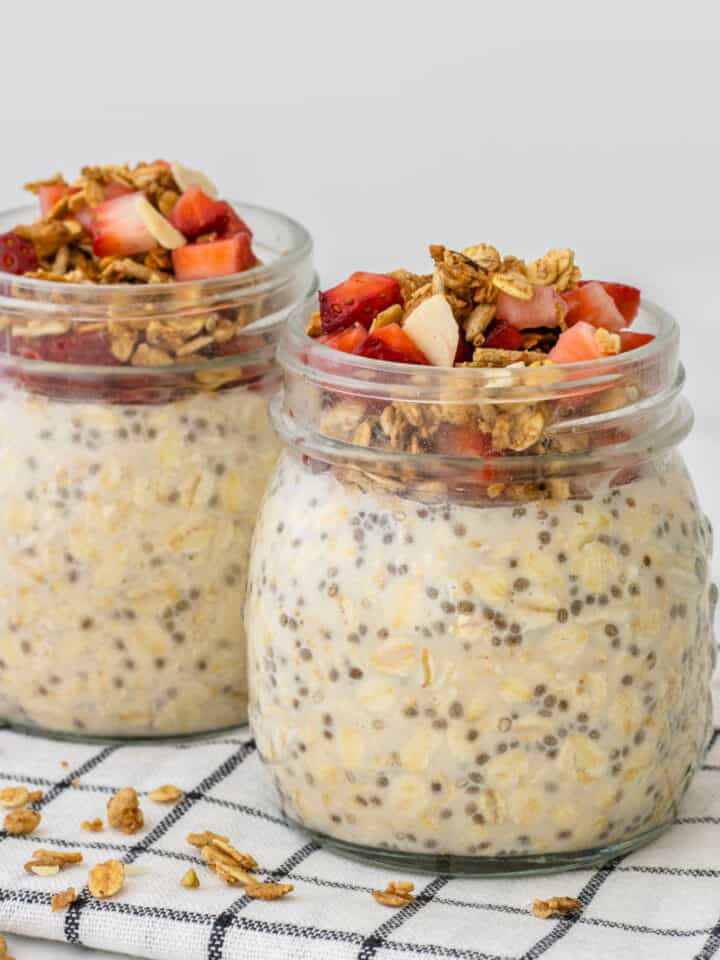 Easy overnight oats in glass jars topped with granola and strawberries