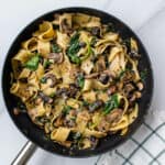 Pappardelle pasta with mushrooms in a pan topped with parmesan and chilli