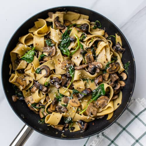 Pappardelle pasta with mushrooms in a pan topped with parmesan and chilli