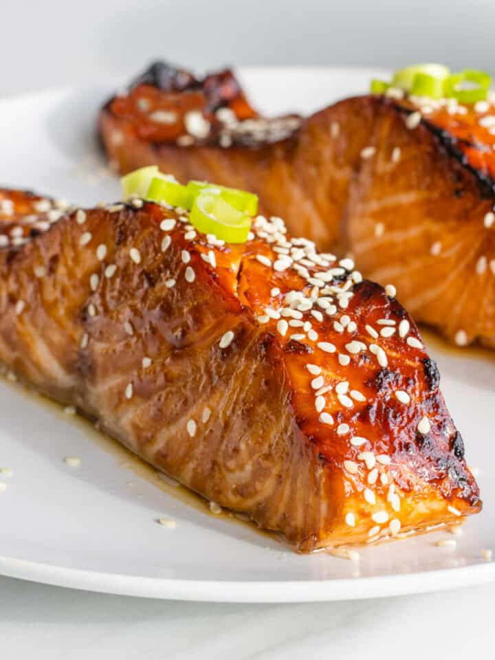 Teriyaki Salmon fillets on a plate topped with sesame seeds and spring onions