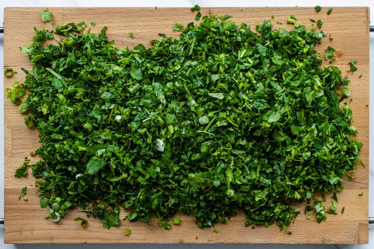 Chopped parsely, cilantro and dill herbs on a chopping board