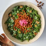 Tahini kale salad with crispy chickpeas served in a bowl and topped with pickled onions
