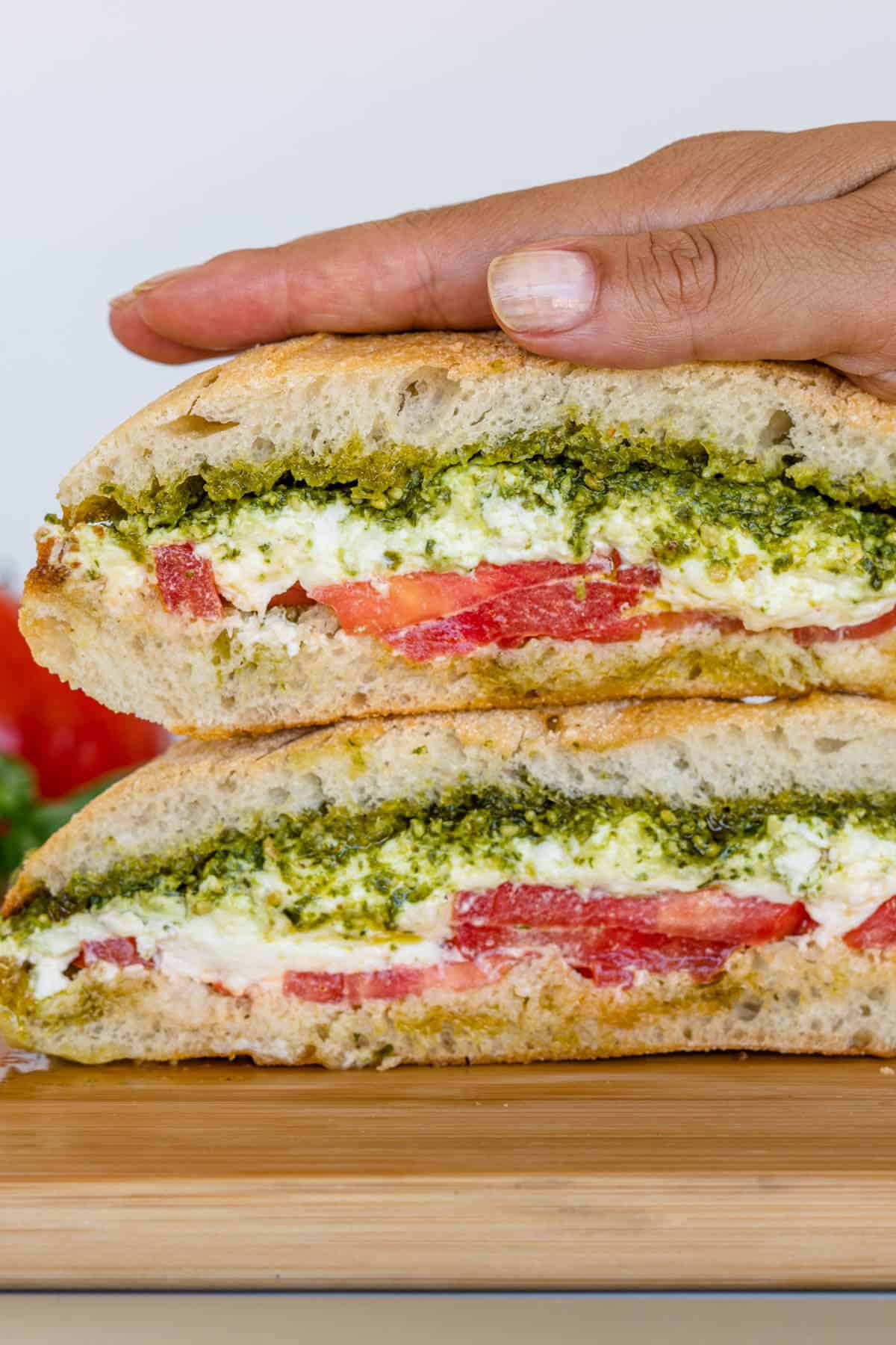 Burrata Caprese Sandwich stacked with hand on top