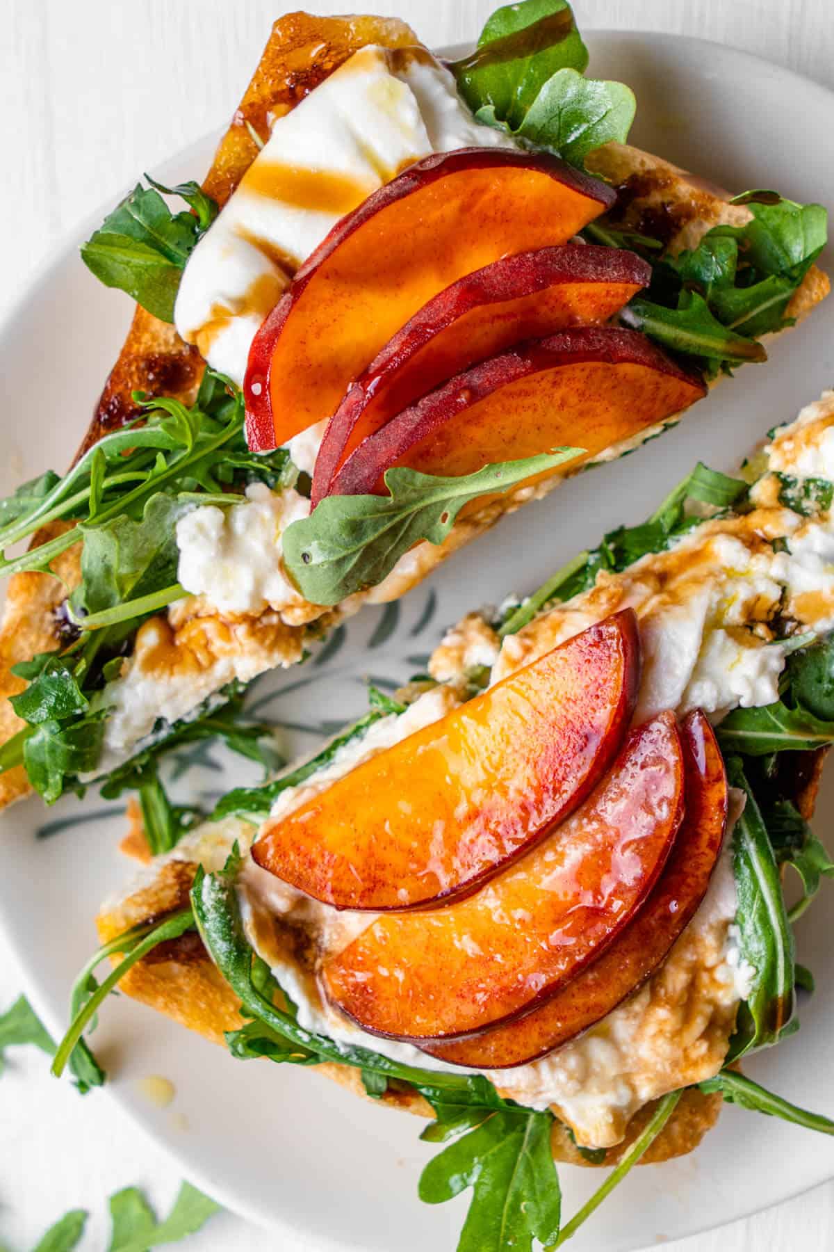 Burrata toast with peach and arugula cut in half