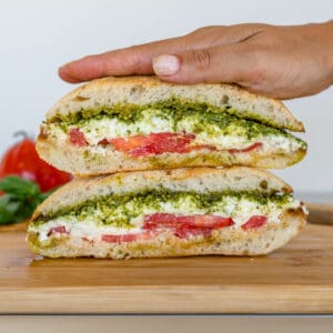 Burrata Caprese sandwich stacked with hand pressing down