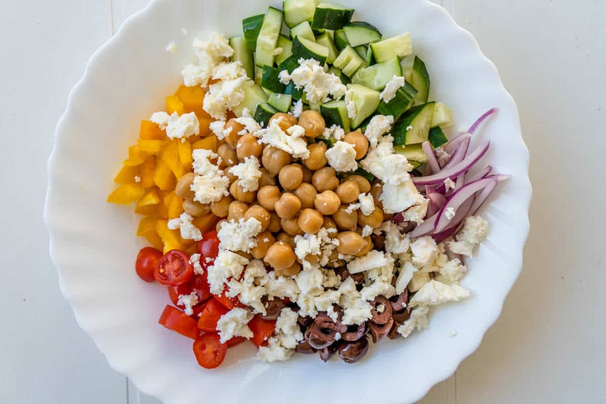 Chickpeas and feta added to chopped ingredients bowl