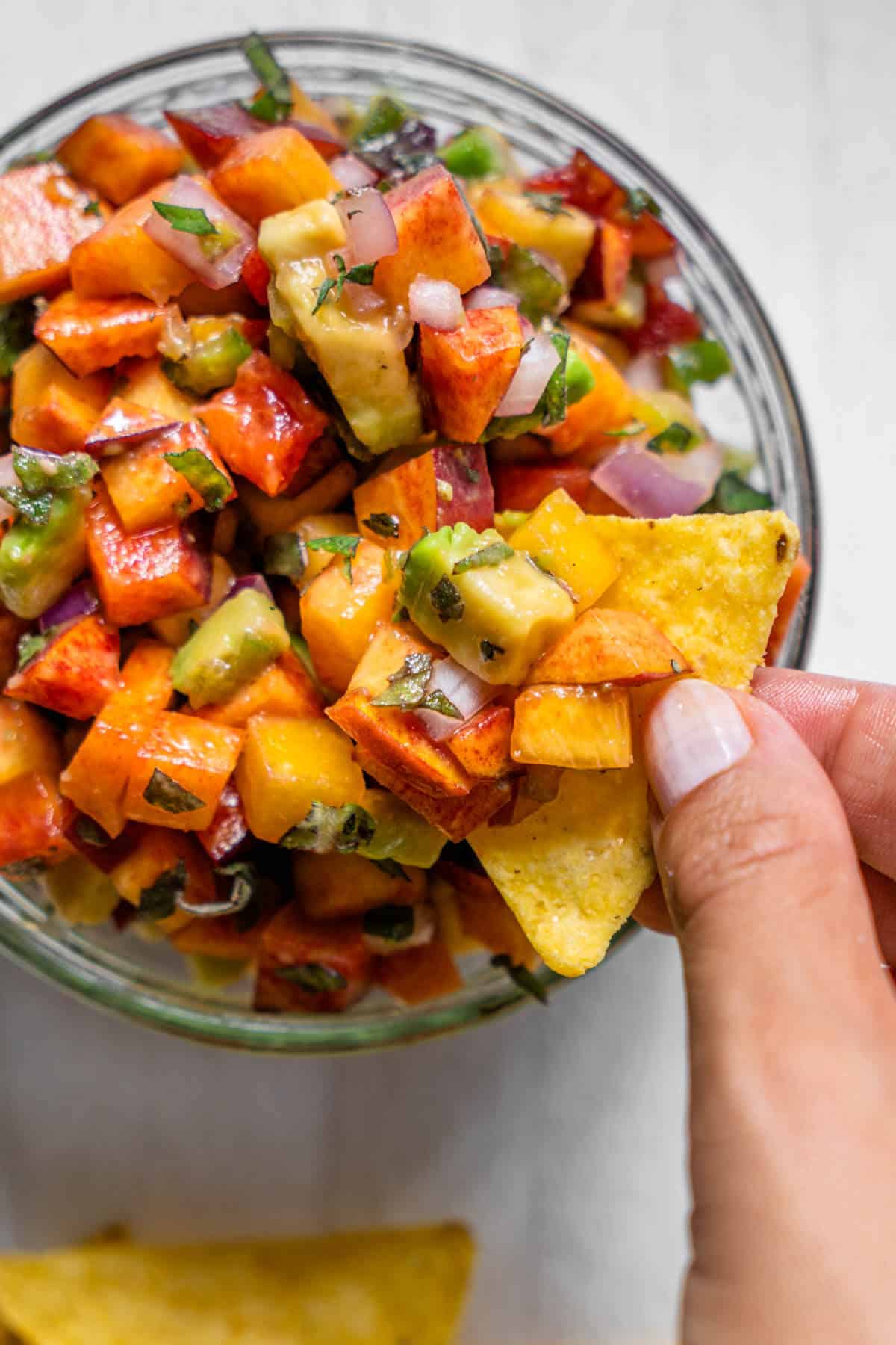 Corn chip being dipped into Peach salsa
