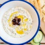 Vegan Tzatziki served in a bowl topped with black olives and olive oil