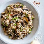 Mushroom pea risotto served in a bowl topped with chilli and parmesan