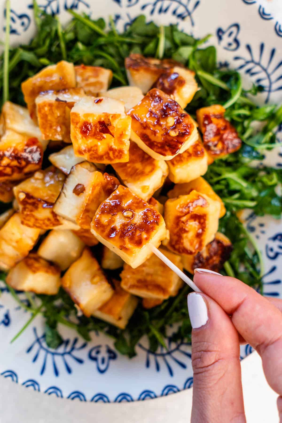 Piece of fried halloumi being picked with a toothpick