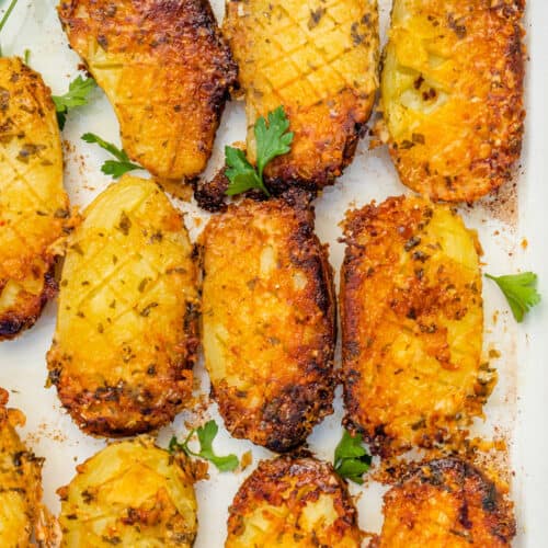 Parmesan crusted potatoes in an oven dish with fresh parsley