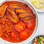 Khoresh Bademjan (Persian Eggplant Stew) served in a pan with Persian rice and shirazi salad on the side