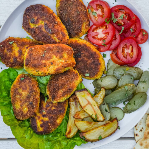 Plate of kotlet Persian patties with tomato, pickles and fries