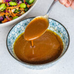 Spoon drizzle of miso dressing into a bowl