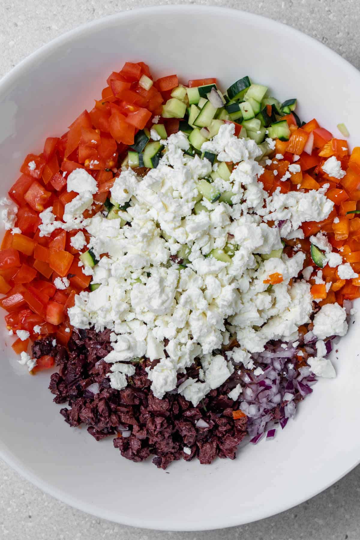 Chopped veggie ingredients with crumbled feta before being mixed