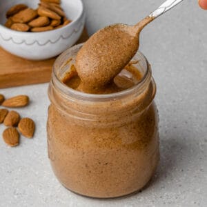 Spoon coming out of jar of almond butter