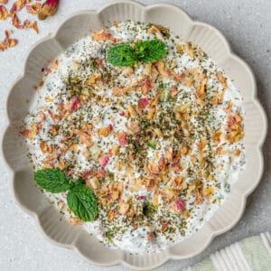 Mast o Khiar served in a bowl topped with mint, walnuts and rose petals