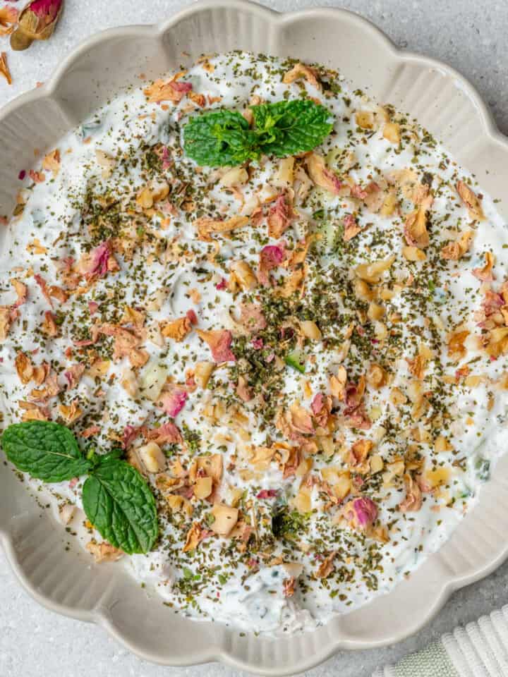 Mast o Khiar served in a bowl topped with mint, walnuts and rose petals