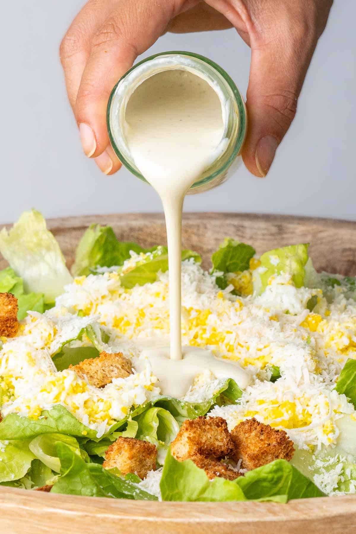 Caesar salad dressing without anchovies being poured over the salad