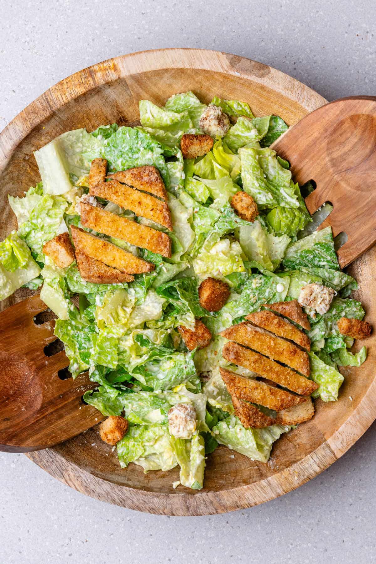 Mixed healthy caesar salad in a bowl with crispy tofu on top