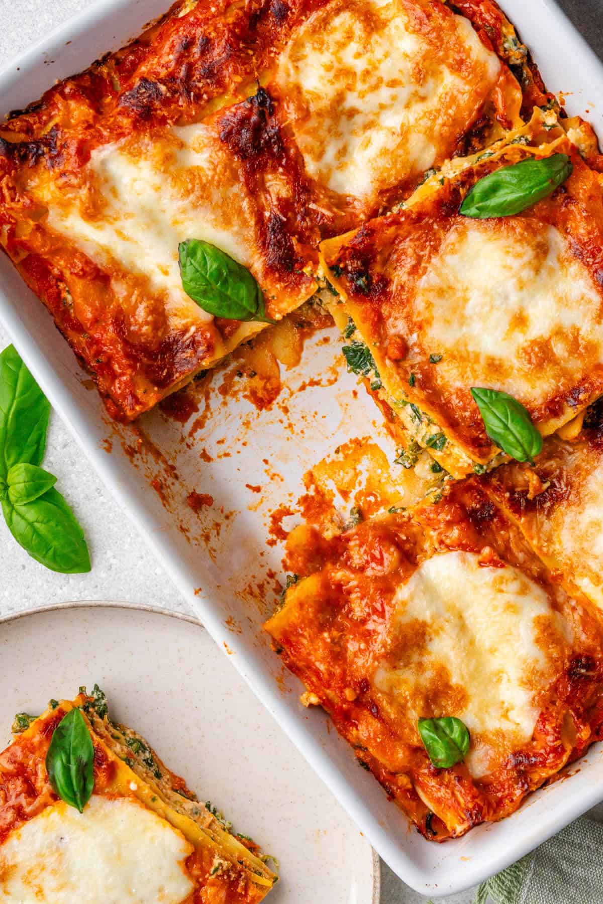Spinach lasagna recipe in dish with a piece missing