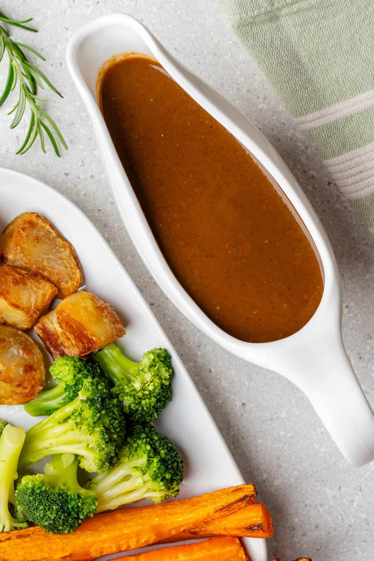 Vegan gravy in a gravy boat with roasted veggies on the side