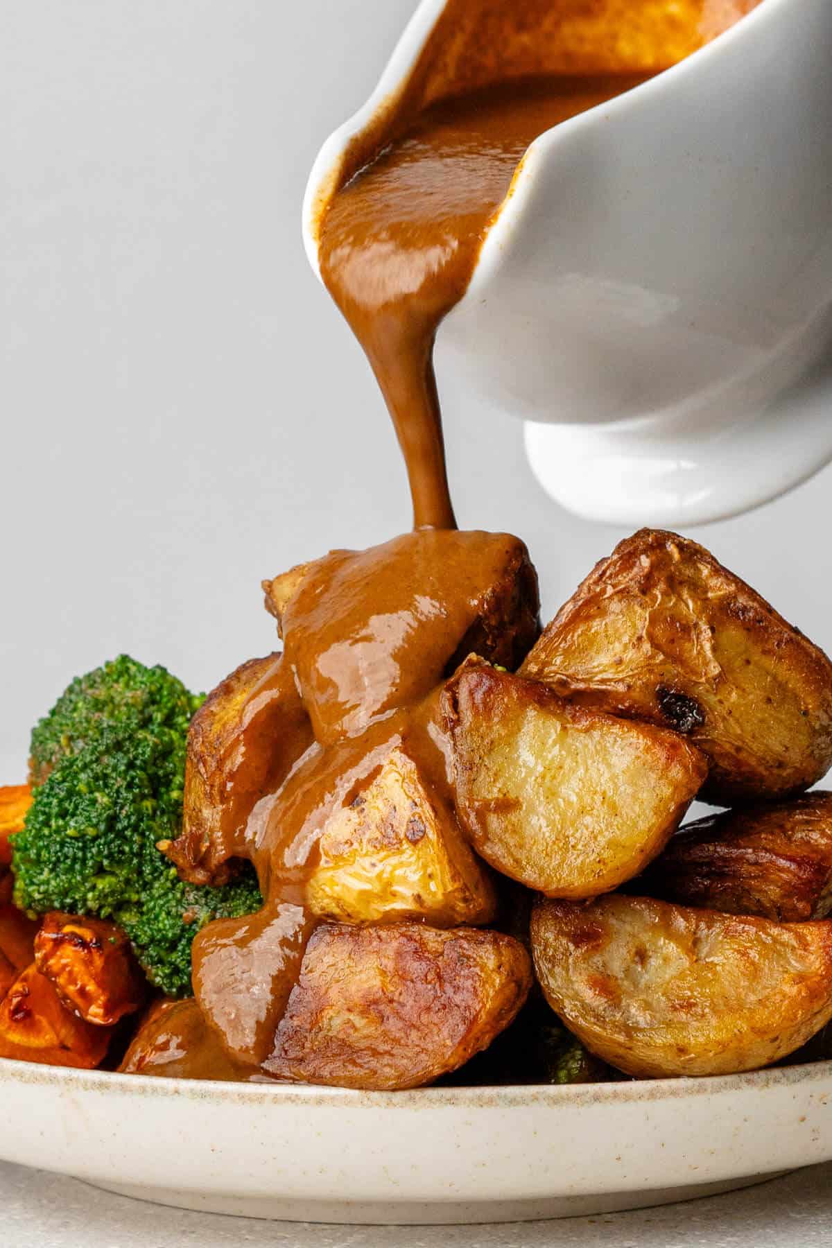 Motion shot of gravy being poured on top of roasted potatoes