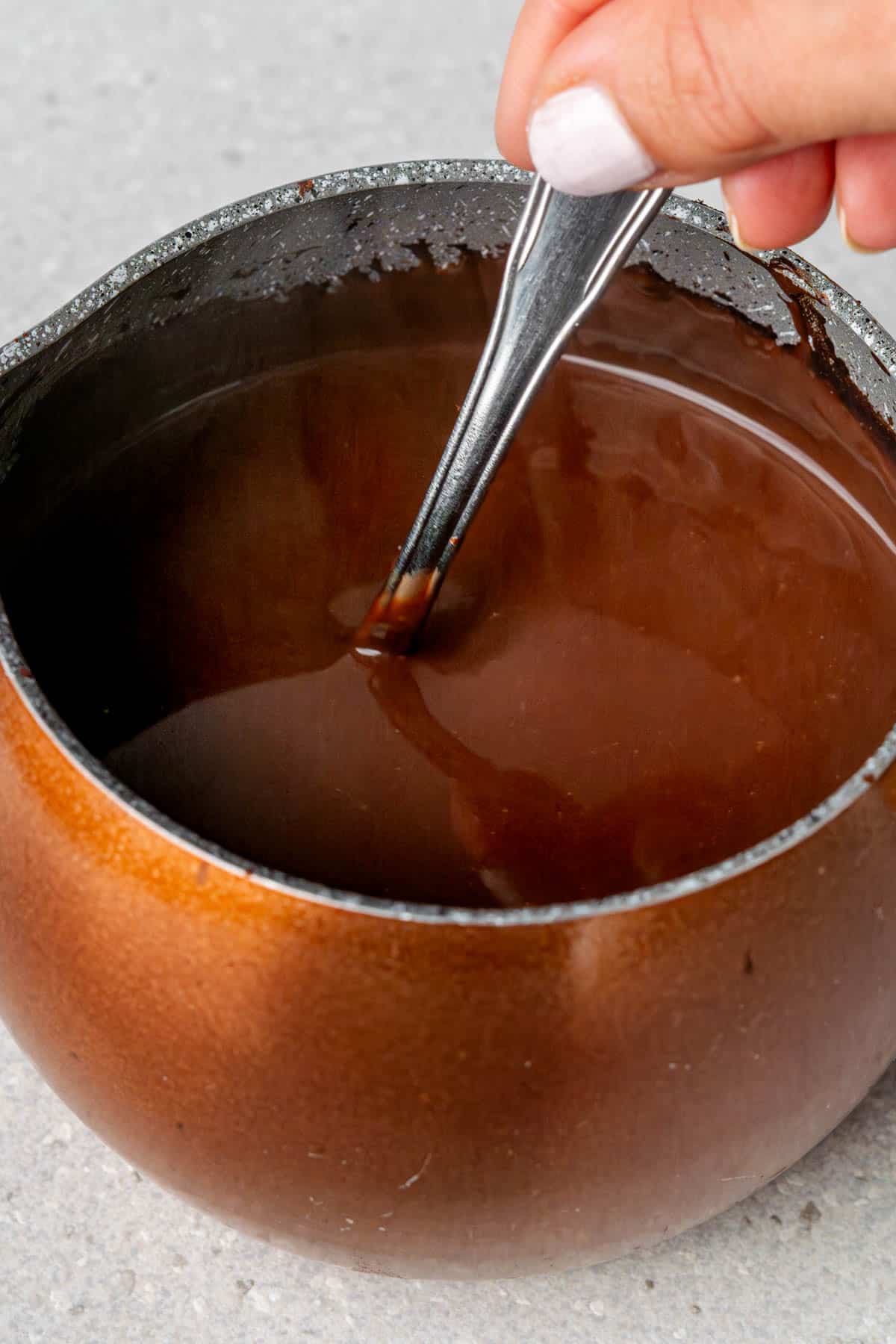 Spoon mixing hot chocolate in a mini pot