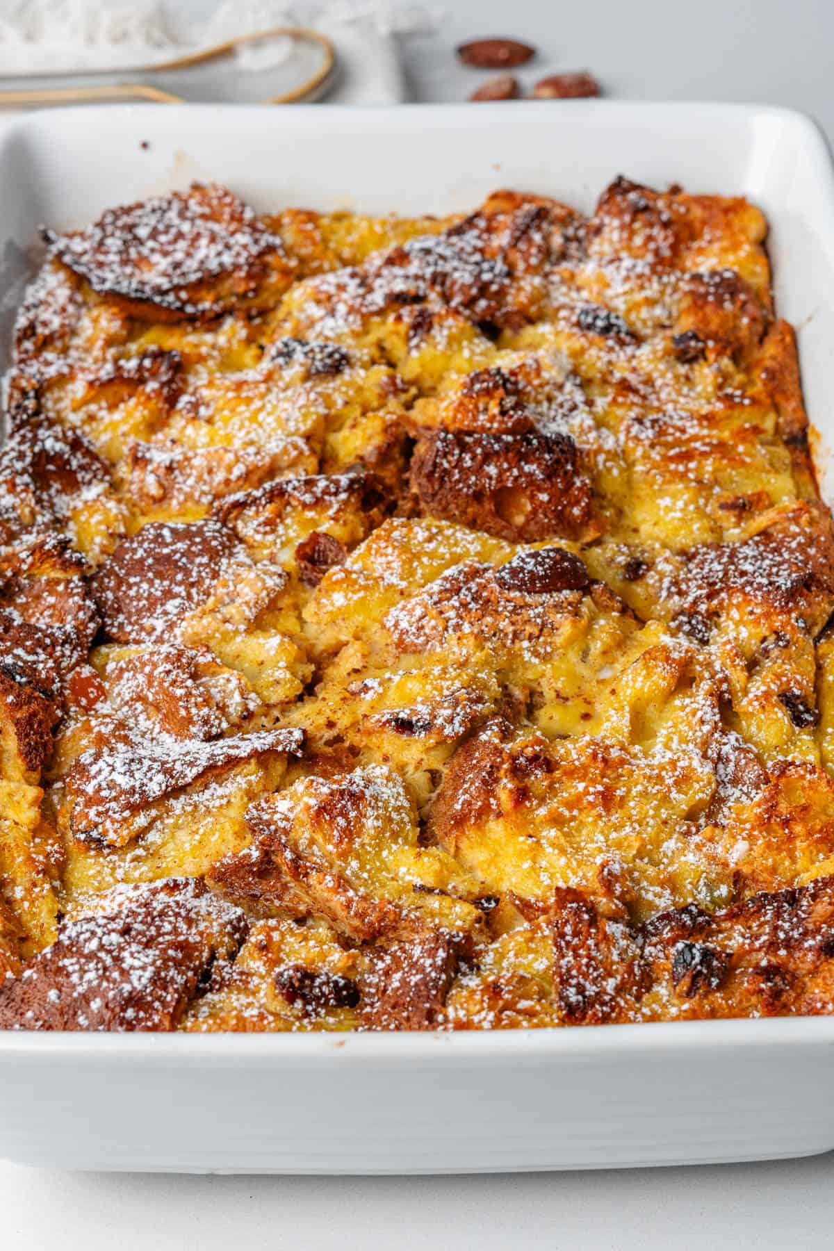 Panettone bread pudding in an oven tray topped with icing sugar