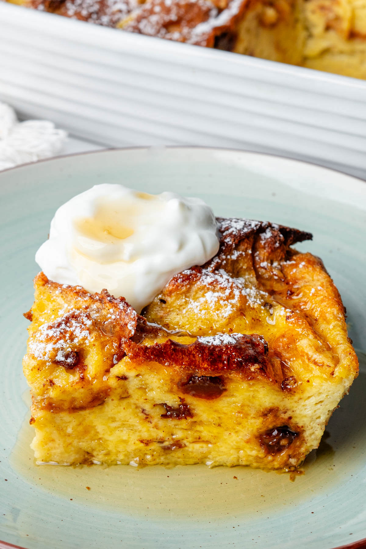 Piece of Panettone bread pudding on a plate, topped with yogurt and maple syrup