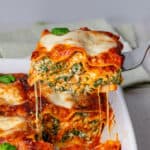 Piece of spinach lasagna being lifted out of a oven dish