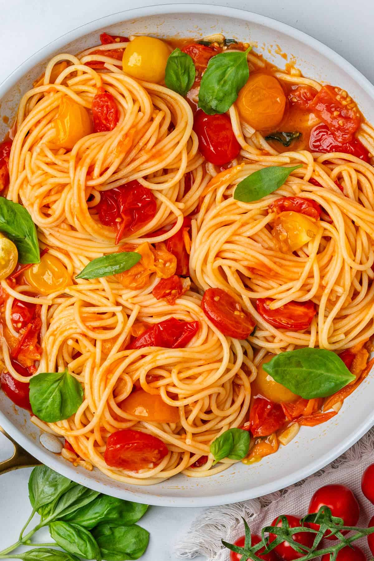 Pan of cherry tomato pasta topped with fresh basil