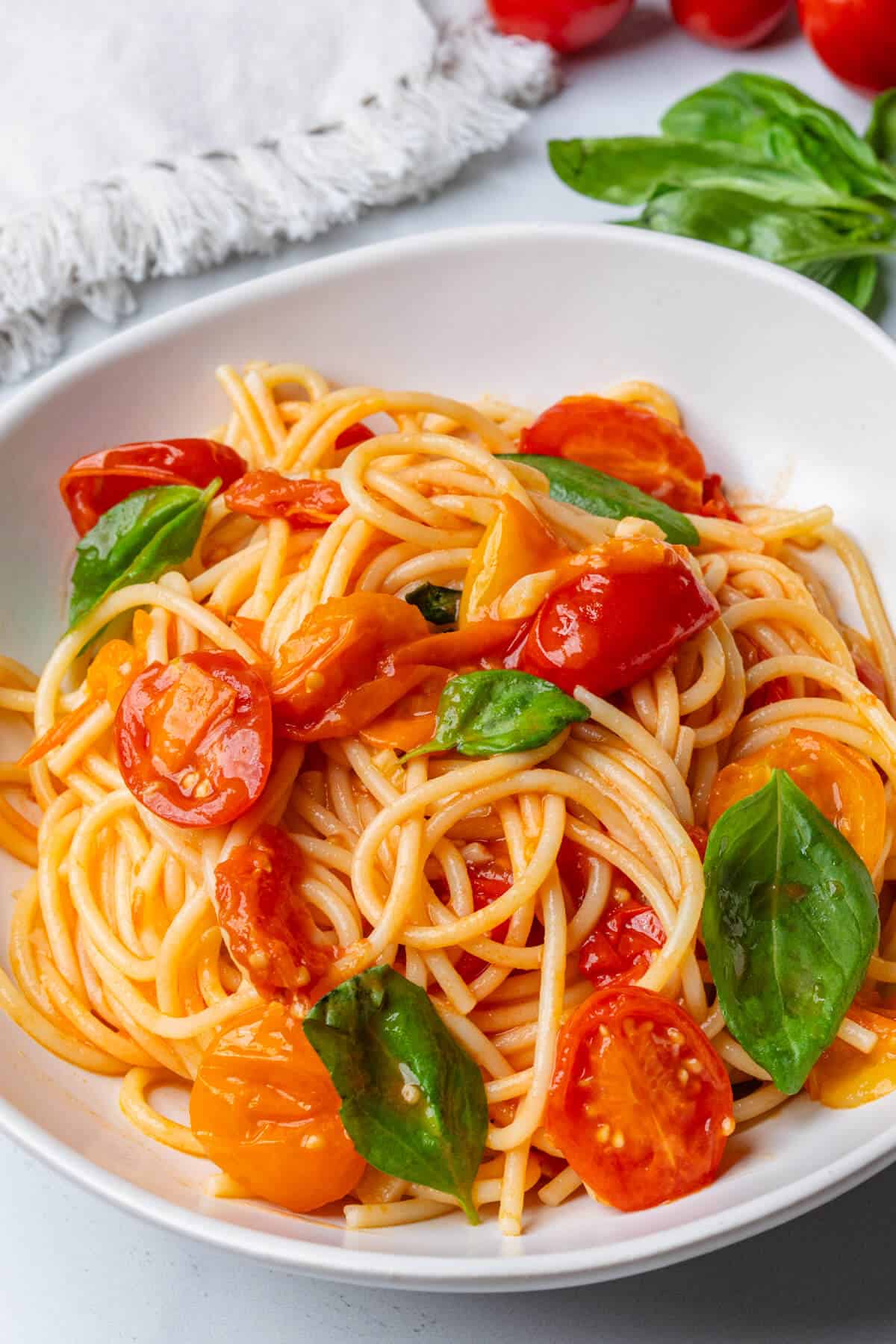 A bowl of pasta with cherry tomatoes and fresh basil