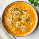 Pastina soup in a bowl with garnish of parsley, parmesan cheese and olive oil
