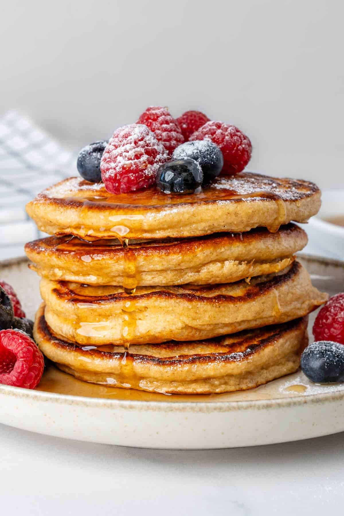 Greek yogurt pancakes topped maple syrup, fresh berries and icing sugar