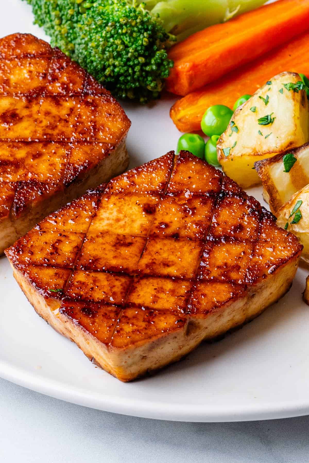 Tofu steaks on a plate with a side of vegetables