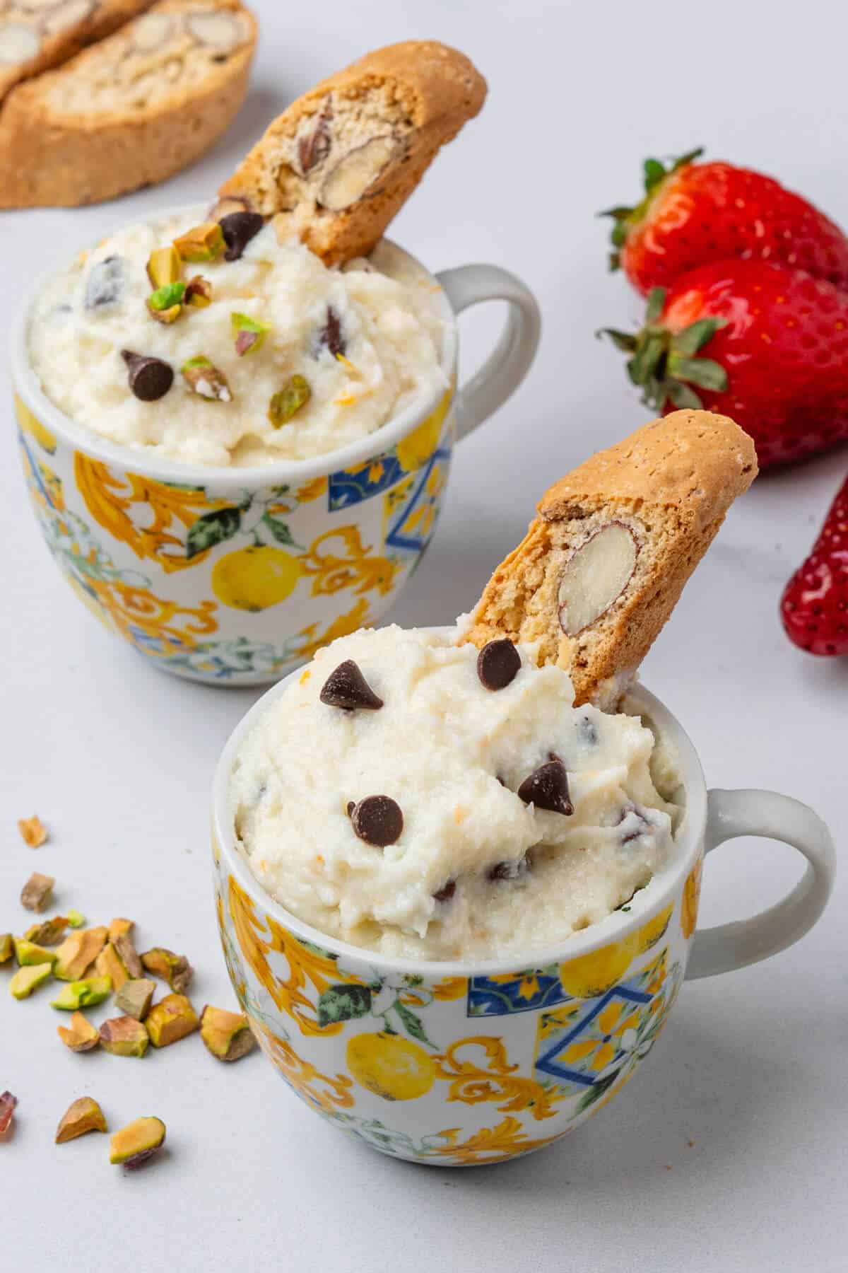 Espresso cups filled with cannoli mixture and a biscotti